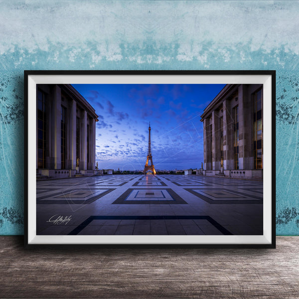 a large, framed photograph of the Eiffel Tower in Paris, France, with the tower illuminated against a blue sky.