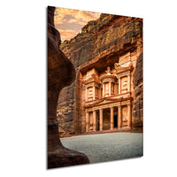 a large, ancient stone structure carved into a cliff face, with a warm, golden glow from the setting sun illuminating the scene.