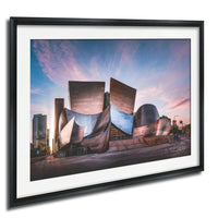 a large, modern building with a unique, angular design, set against a colorful sky at sunset.