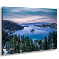 A serene landscape featuring a deep blue lake surrounded by a forested mountain range, with a small island in the center of the lake. The sky is filled with clouds, creating a picturesque and tranquil atmosphere.