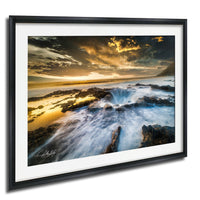 The image is a framed photograph depicting a dramatic natural landscape with a waterfall, rocky terrain, and a dramatic sky with clouds and sun rays.