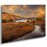 A picturesque rural landscape with a white farmhouse nestled among the rolling hills, a winding stream, and a vibrant autumnal sky.