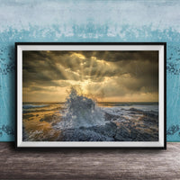 The image is a framed photograph of a dramatic ocean scene, with crashing waves and a dramatic sky filled with clouds and sunbeams.