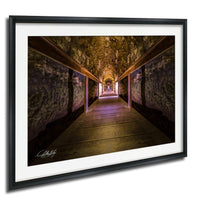 a long, dimly lit tunnel with a wooden walkway running through it, illuminated by a purple light at the end.