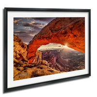 a stunning natural landscape with a large, vibrant orange rock formation that resembles a tunnel or arch, set against a breathtaking backdrop of a sunset sky.