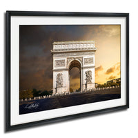 the Arc de Triomphe, a famous monument located in Paris, France. The photograph is framed and displayed on a wall, showcasing the iconic structure against a dramatic sky.