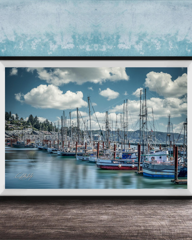 A framed photograph of a harbor with numerous sailboats docked in the water, set against a backdrop of a cloudy sky.