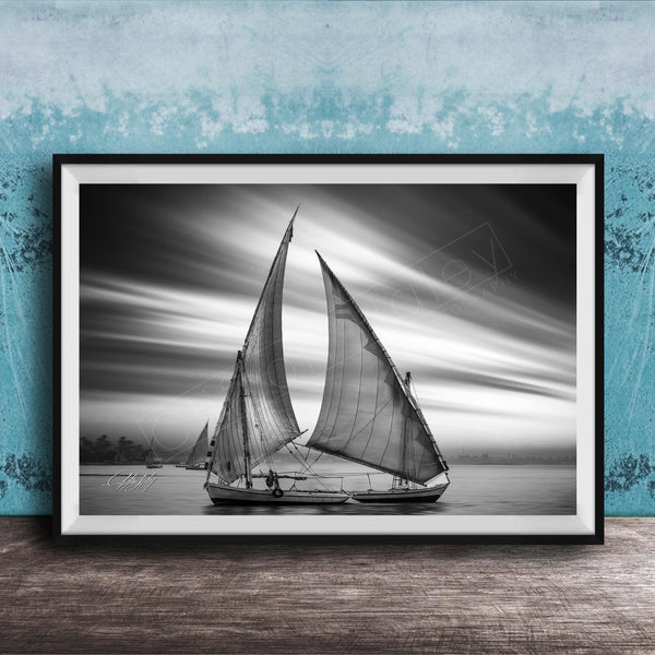 This luxury black and white fine art photograph captures a felucca sail boat drifting along the Nile River at sunset near Luxor, Egypt. Soft fog and minimalist composition create a timeless, monochrome aesthetic rooted in Egyptian river culture. Ideal for collectors and interior designers seeking refined, museum-quality wall art that embodies elegance, simplicity, and enduring calm. black white nile river art, felucca sailboat wall decor, luxor egypt monochrome print, luxury minimalist wall art