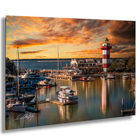 a serene harbor scene at sunset, with boats docked in the calm waters and a lighthouse standing tall in the background. The sky is filled with vibrant orange and pink hues, creating a picturesque and tranquil atmosphere.