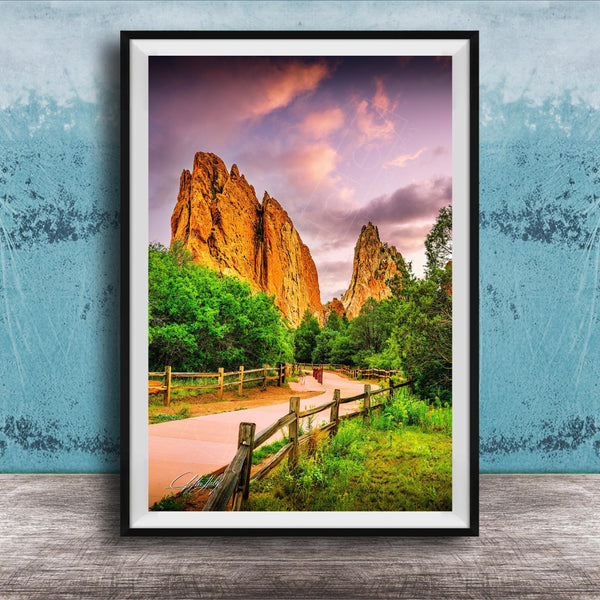 A framed photograph of a scenic landscape with towering rock formations, a wooden fence, and a vibrant sky with clouds.