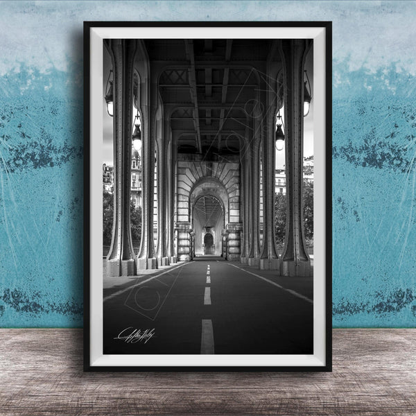 A black and white photograph of a long, narrow hallway with tall columns and arches, leading to a doorway at the end. The hallway appears to be part of a larger architectural structure, possibly a building or a church.