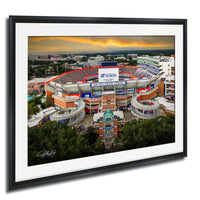 a large sports stadium with a large sign that reads "UF FLORIDA" against a backdrop of a cloudy sky and a sunset.