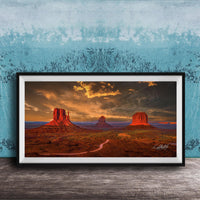A framed photograph depicting the iconic rock formations of Monument Valley, with a dramatic sunset sky in the background.