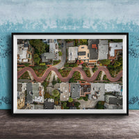 The image is an aerial view of a winding road in a residential area, with houses and trees lining the road.