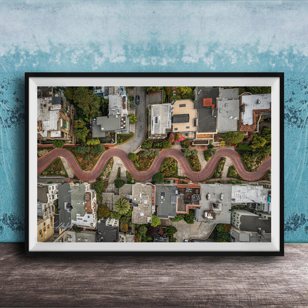 The image is an aerial view of a winding road in a residential area, with houses and trees lining the road.