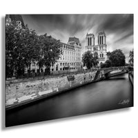 a serene cityscape with a river running through it, flanked by historic buildings and trees. The sky is filled with clouds, creating a dramatic backdrop for the scene.