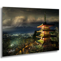 A multi-tiered pagoda-style building illuminated at night, with a mountainous landscape and a stormy sky in the background.