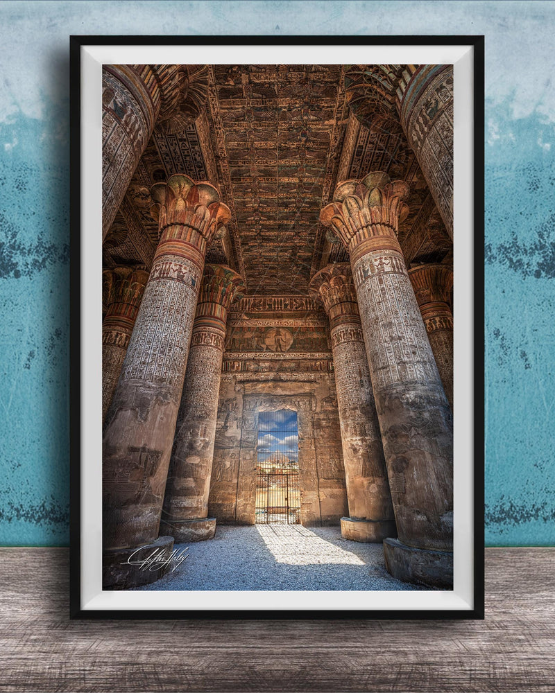 an ancient Egyptian temple with towering columns and intricate carvings, set against a blue wall with a textured pattern.