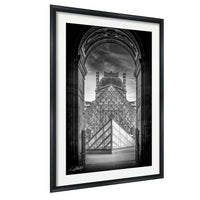 A black and white photograph of the Louvre Museum in Paris, France, with the iconic glass pyramid structure of the museum prominently featured in the center of the frame.