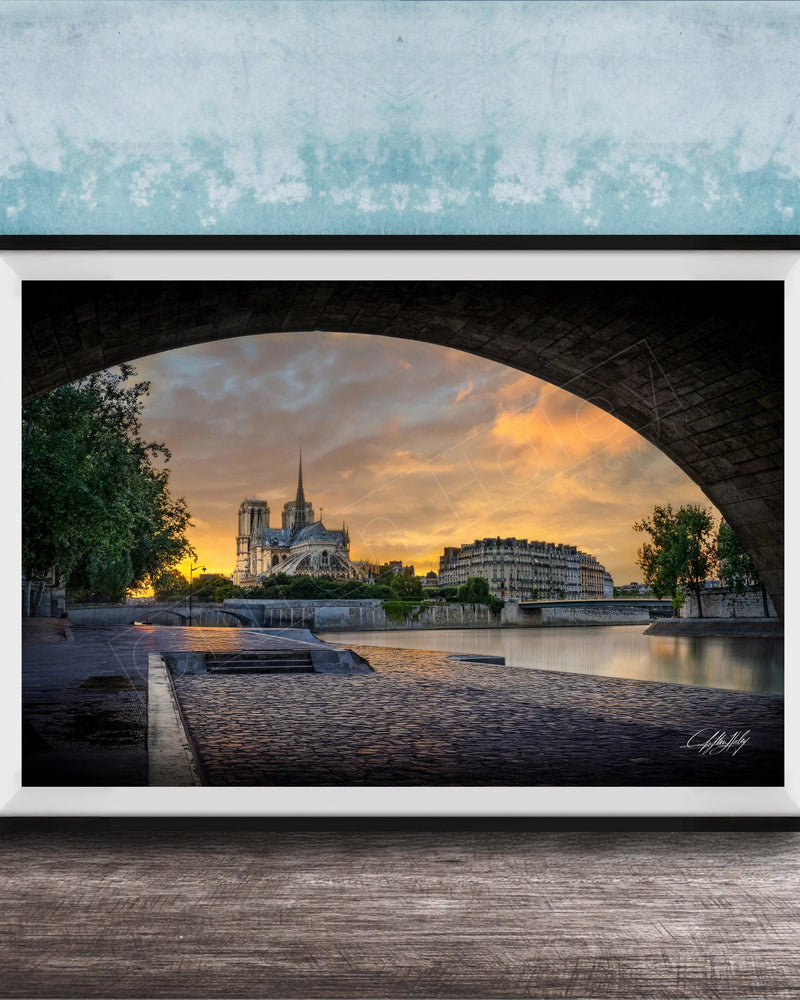 a serene cityscape at sunset, with a large cathedral in the background and a stone bridge arching over a river. The sky is filled with warm, golden hues, creating a picturesque and tranquil atmosphere.