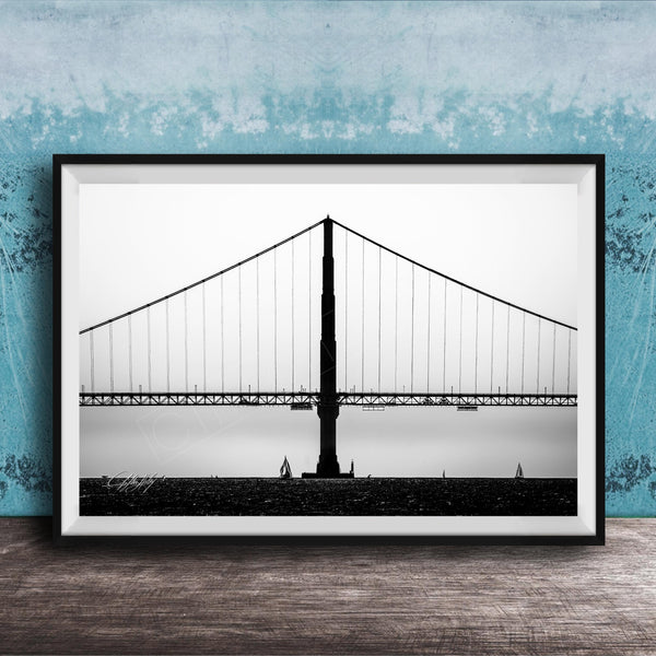 A black and white photograph of the Golden Gate Bridge in San Francisco, California, with a blue textured wall in the background.