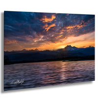 a breathtaking sunset over a mountain range, with the sun's rays reflecting off the calm waters below.