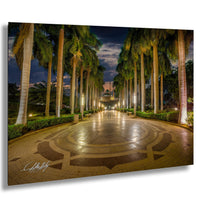 A well-lit, circular walkway lined with palm trees and illuminated by warm lighting, creating a serene and inviting atmosphere.