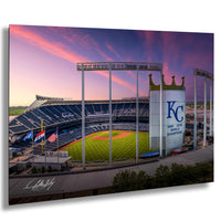 A panoramic view of a baseball stadium at sunset, with the Kansas City Royals logo prominently displayed on the field.