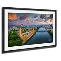 The image is a framed aerial view of the Palace of Westminster, also known as the Houses of Parliament, in London, England. The photograph is taken from a high vantage point, providing a panoramic view of the iconic building and its surroundings.