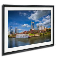 a cityscape with a river running through it, featuring a large white boat on the water. The city skyline includes tall buildings and skyscrapers, creating a vibrant and bustling urban environment.
