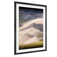 The image is a framed photograph of a desert landscape with sand dunes and a hazy, golden-hued sky.