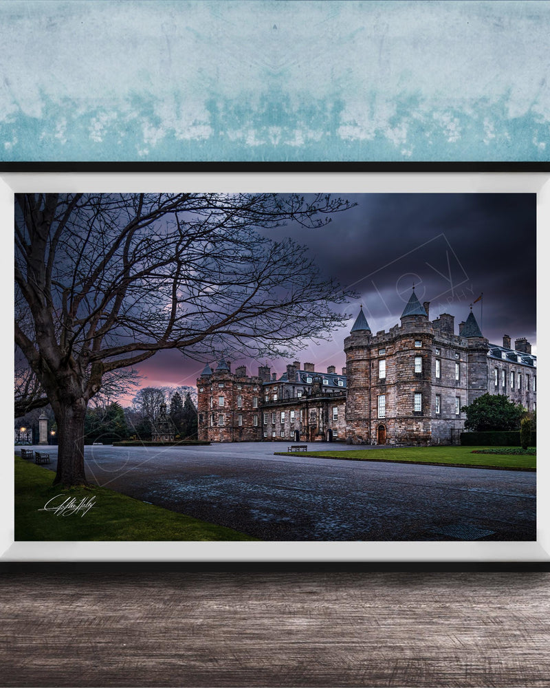 A framed photograph of a castle with a tree in the foreground, set against a dark, cloudy sky.