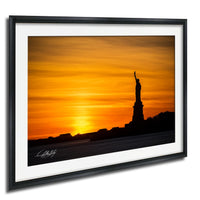 a silhouette of the Statue of Liberty against a vibrant sunset sky.
