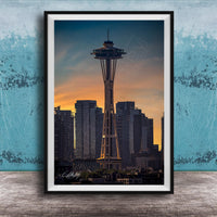 A framed photograph of the Space Needle in Seattle, with the city skyline in the background at sunset.