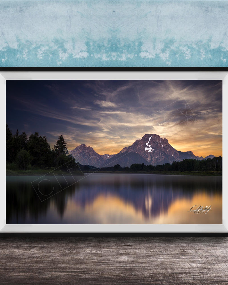 The image is a framed photograph of a serene mountain landscape at sunset, with a calm lake reflecting the vibrant colors of the sky.