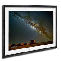 a desert landscape at night, with a starry sky and a large sand formation in the foreground.