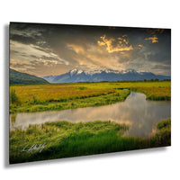 a serene landscape with a winding river, lush green fields, and majestic snow-capped mountains in the background under a dramatic cloudy sky.