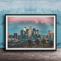 A framed photograph of the Los Angeles skyline at sunset, with the city's skyscrapers and mountains in the background.
