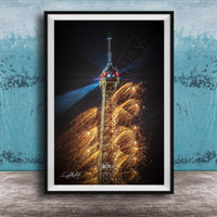 A framed photograph of the Eiffel Tower with a fireworks display in the background, creating a vibrant and colorful scene.