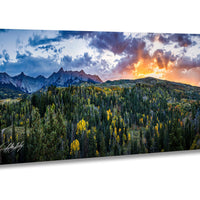 a breathtaking mountainous landscape with a vibrant sunset sky, lush forests, and snow-capped peaks in the distance.