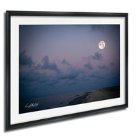 a serene night scene with a full moon illuminating a cloudy sky over a beach.