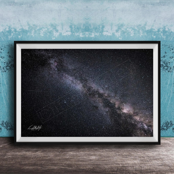 The image is a framed photograph of the night sky, depicting a vast, starry galaxy.