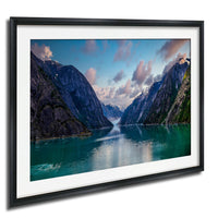 a serene mountain landscape with a calm lake in the foreground, surrounded by towering, snow-capped peaks under a picturesque blue sky with wispy clouds.