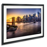 a cityscape with a bridge and skyscrapers in the background, with the sun setting over the water.
