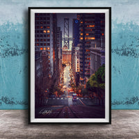 A framed photograph depicting a city street at night, with tall buildings and a bridge in the background. The street is illuminated by streetlights and the glow of the buildings, creating a vibrant and dynamic scene.