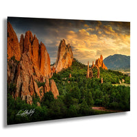 A breathtaking landscape featuring towering red rock formations against a vibrant sunset sky, with lush greenery and distant mountains in the background.