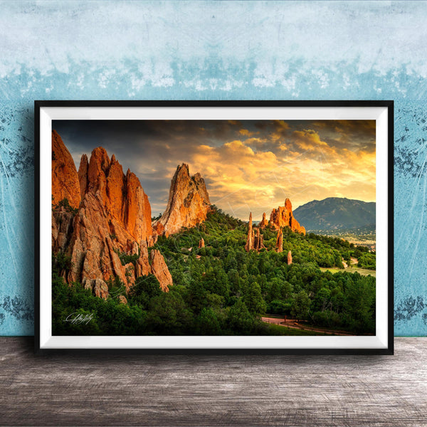 A framed photograph of the Garden of the Gods, a famous rock formation in Colorado, with its distinctive red rock formations and lush green vegetation.