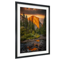 a breathtaking view of a majestic mountain range, with a river flowing through the foreground and surrounded by lush greenery. The sky is filled with vibrant colors, creating a stunning backdrop for the towering peaks.