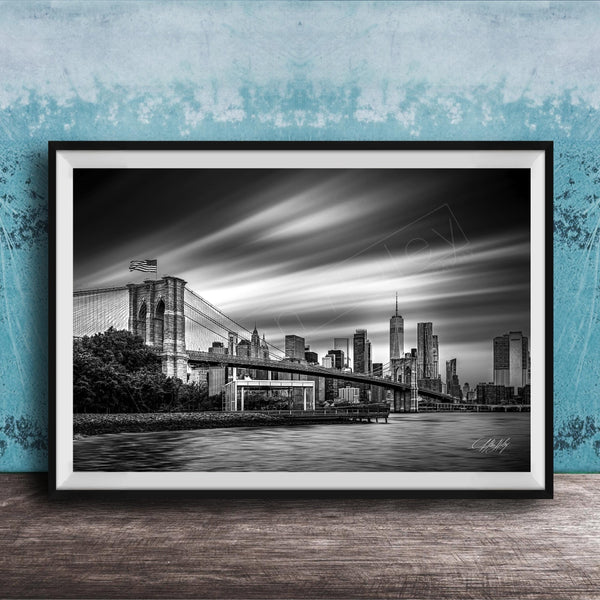 A black and white photograph of the Brooklyn Bridge in New York City, with the city skyline in the background.
