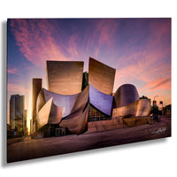 a modern, curved building with a metallic, angular design set against a vibrant sunset sky.
